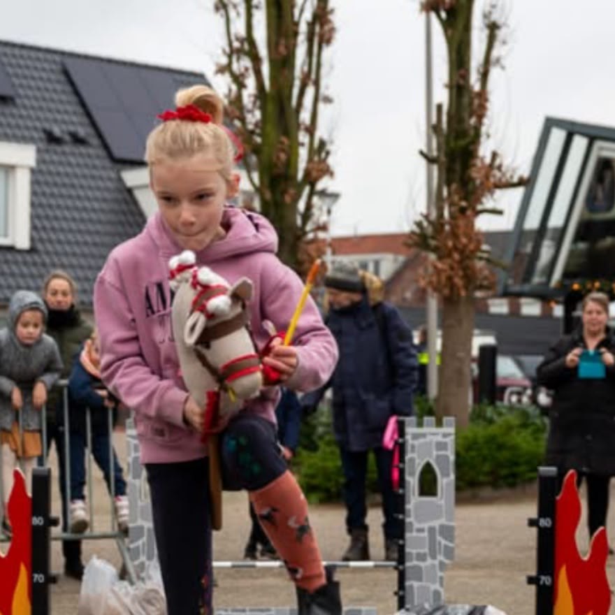 Meisje springt met haar hobby horse over een hindernis op de Goorse Wintermarkt